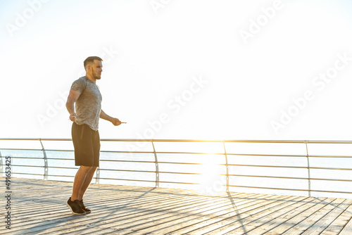 Athletic man jumping rope in the early morning on beach