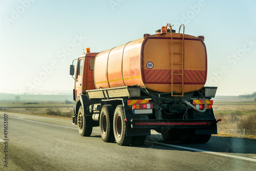 Orange Tank Truck on a highway road under blue sunrise sky
