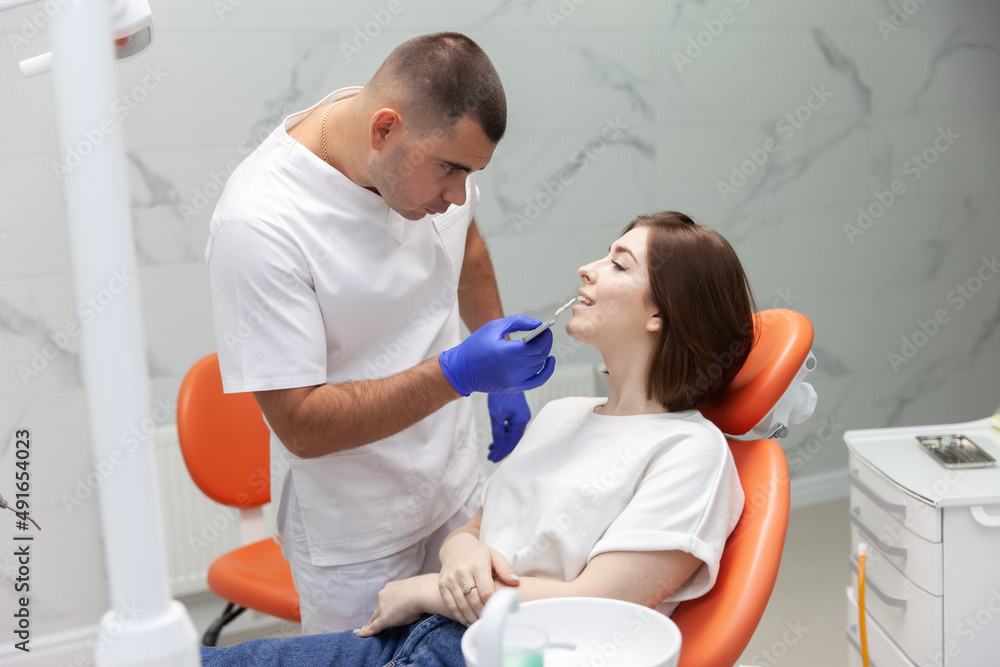 Professional dentist selects the color tone of the teeth for the female patient in the dental clinic Professional dentist selects the color tone of the teeth for the female patient in the dental clinic