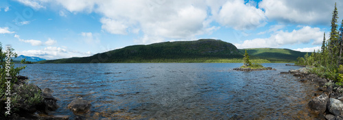 Panoramic view over lake Stuor Dahta in Laponia. Sweden Lapland summer nature. Mountains, birch trees, spruce forest, rock boulders and grass. Blue sky, clouds and clear water. photo