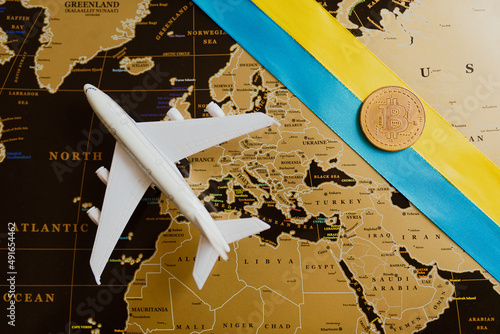 The plane and the Ukrainian flag on the background of the map with bitcoin