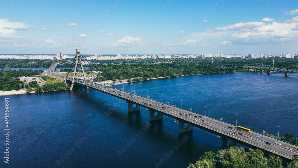 Traffic of cars on a large bridge over the river in a cityscape on a sunny day