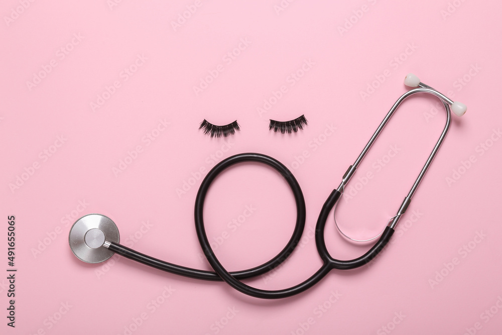 Conceptual pop shot with stethoscope and false eyelashes on pink background Conceptual pop shot with stethoscope and false eyelashes on pink background