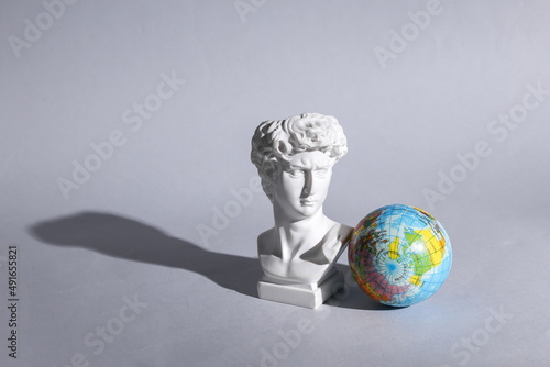 Antique David bust with globe on gray background with shadow. Conceptual pop. Minimal still life. Creative travel layout