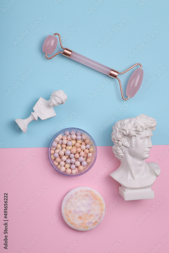 Beauty products and antique busts on a blue-pink pastel background. Minimal layout Beauty products and antique busts on a blue-pink pastel background. Minimal layout