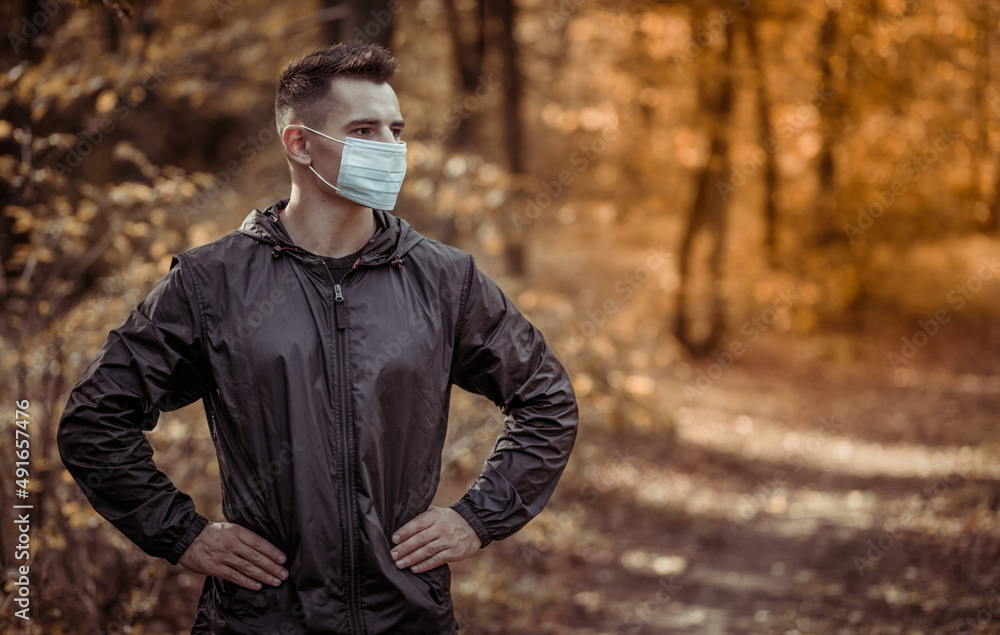 Portrait of active man in medicine face mask in forest Portrait of active man in medicine face mask in forest