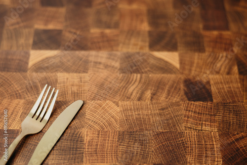 A dining gold fork and knife sitting on top of an empty butcher block counter top in a kitchen