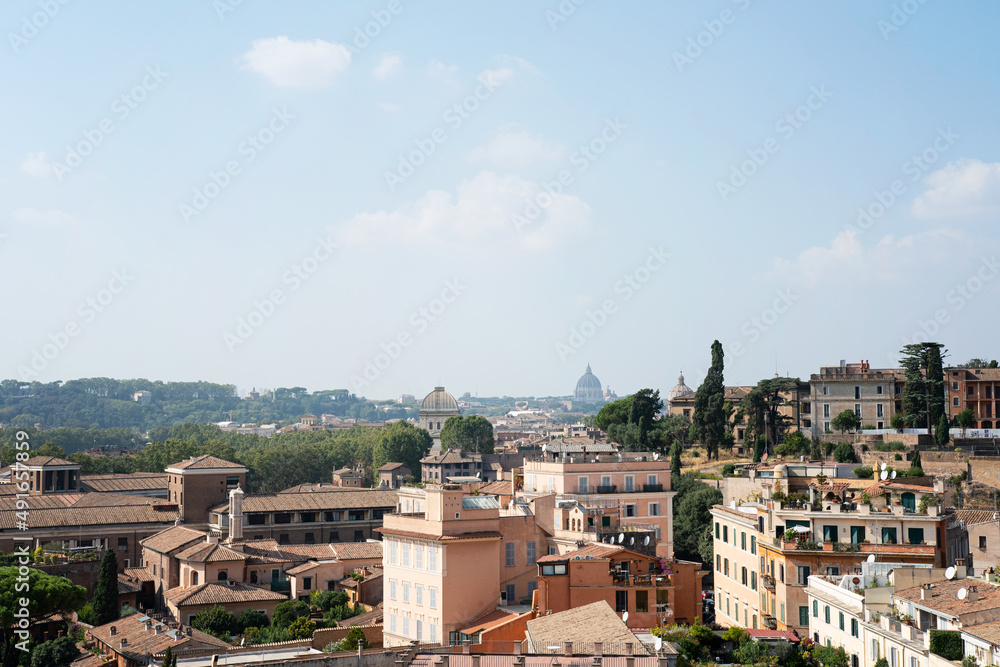 View of the city of Rome on a beautiful summer day. Cityscape with architecture and old buildings. Far away in the skyline the church St. Peter's Basilica can be seen. Photo taken in Rome, Italy.