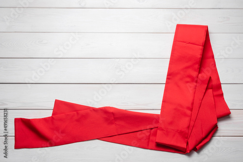 Red waistband from the Kimono on the white wooden table flat lay background with copy space.