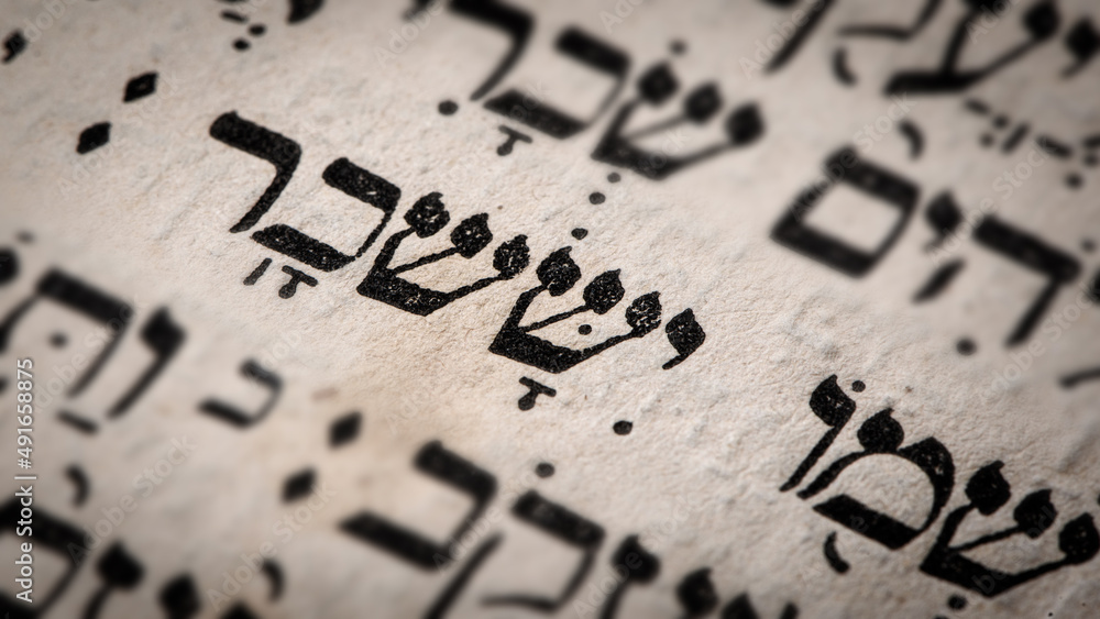 Hebrew word in Torah page. English translation is name Issachar, the founder of the Israelite Tribe of Issachar. Fifth of six sons of Jacob and Leah. Selective focus. Closeup.