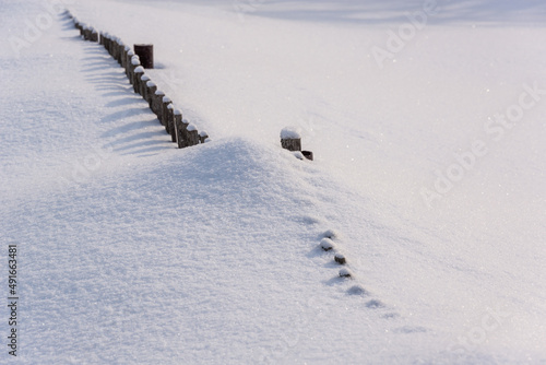 The wooden fence is completely covered with snow.