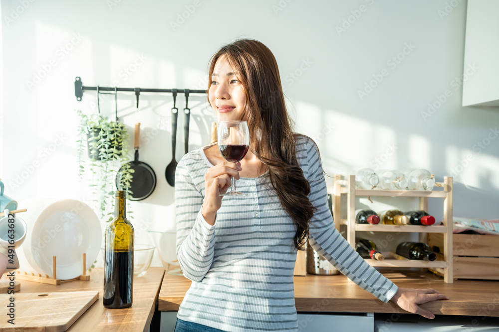 Asian attractive young woman drinking wine in glass in kitchen at home. Asian attractive young woman drinking wine in glass in kitchen at home.