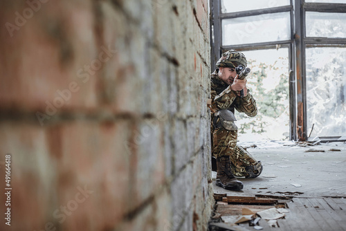 Strong military man in the form holds in hands a big rifle, looks like opponents from the corner. © Тарас Нагирняк