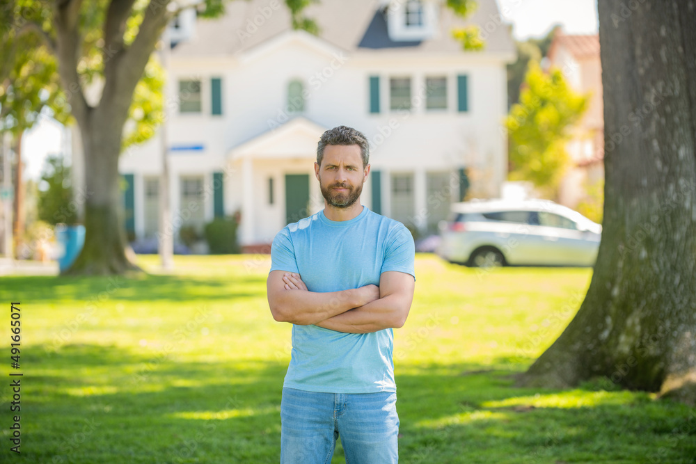 confident unshaven guy standing near new home, buying house