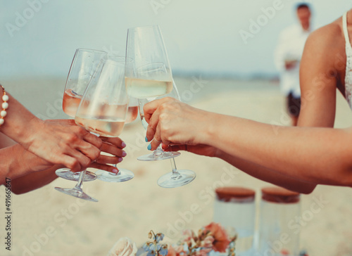 Cheerful women proposing toast on beach