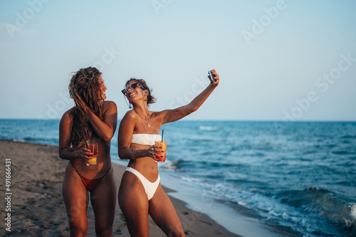 Friends enjoying vacation together and taking selfie on the beach using smartphone © Zamrznuti tonovi