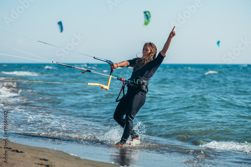 Young sporty woman using control bar to lift her kite up for kitesurfing