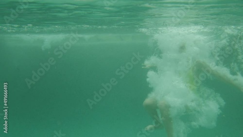 Beautiful young woman in yellow swimsuit falling, jumping. Suffocate. Under the water. Blond girl swimming in the ocean, pool, sea, lake. Water. Bikini. Slow motion