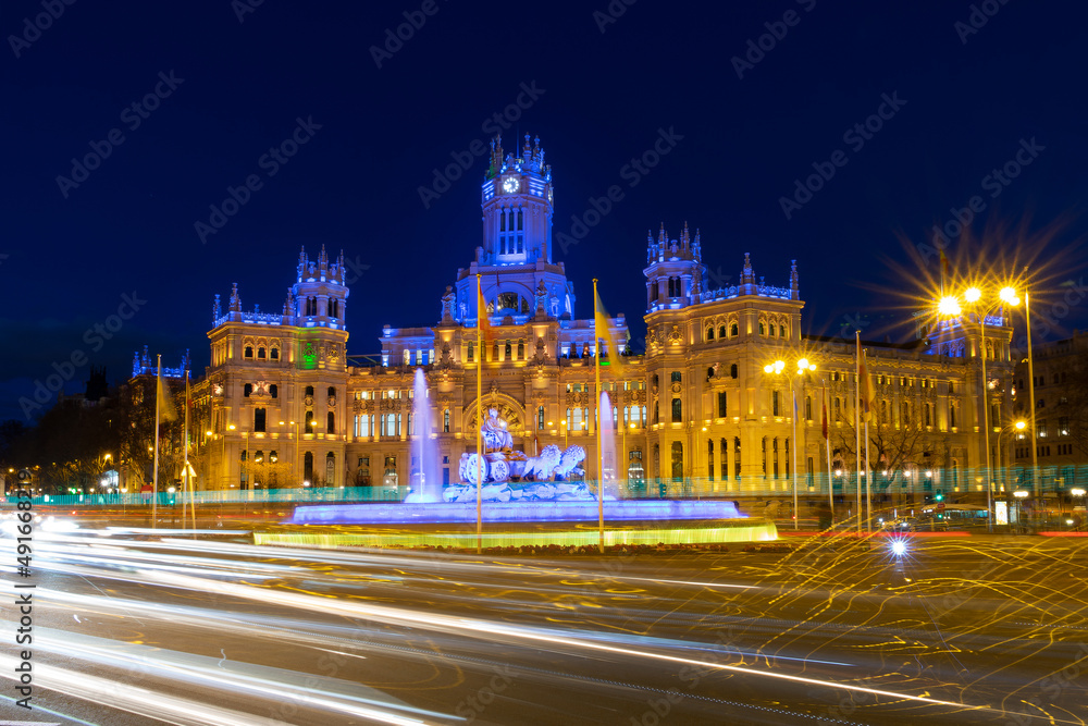 City Hall of Madrid, Spain illuminated at night in blue and yellow with a flag of Ukraine
