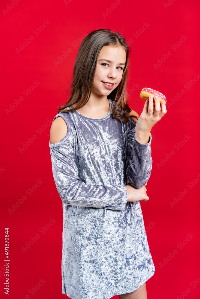 portrait of a beautiful girl in a gray dress with loose hair. teenager with donut. on a red background portrait of a beautiful girl in a gray dress with loose hair. teenager with donut. on a red background