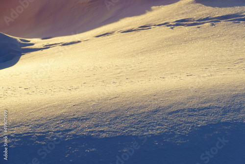 Background of snowdrifts in backlight of warm spring sunlight