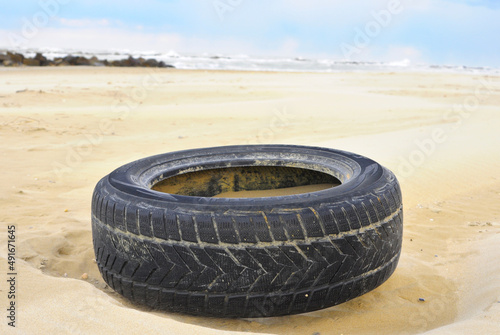 vecchia gomma pneumatico abbandonato in spiaggia. inquinamento mare photo