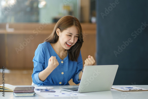 Fotografia Pretty Asian businesswoman sitting on a laptop And the work came out successfully and the goal was achieved, happy and satisfied with her