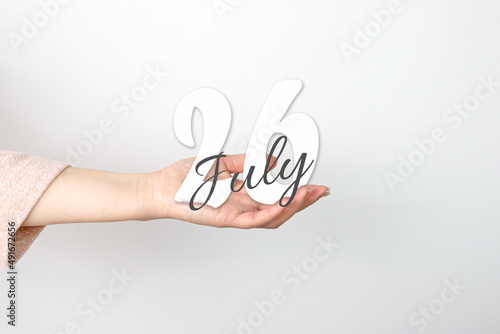 July 26th. Day 26 of month, Calendar date. Calendar Date floating over female hand on grey background. Summer month, day of the year concept.