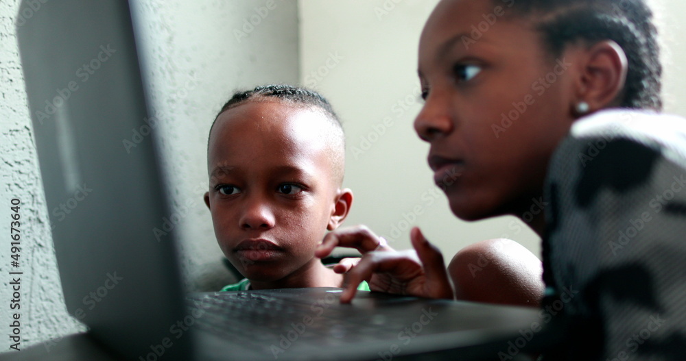 Children browsing the internet on laptop. little brother and sister in front of computer screen. African black ethnicity Children browsing the internet on laptop. little brother and sister in front of computer screen. African black ethnicity