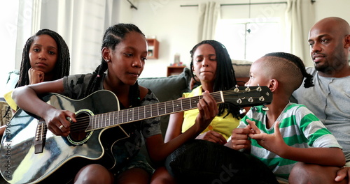 Casual black African family bonding thogether through music guitar. Daughter playing musical instrument © Marco