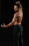 muscular man. athlete posing in a black T-shirt and jeans. studio portrait