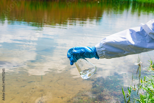 Analysis, water sample from the river, lake. A gloved hand collects water in a test tube.