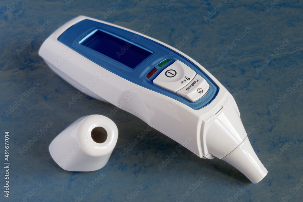 Forehead and ear infrared thermometer with LCD display and fever alarm isolated on colorful worn textured studio background. Medicine and technology. Forehead and ear infrared thermometer with LCD display and fever alarm isolated on colorful worn textured studio background. Medicine and technology.