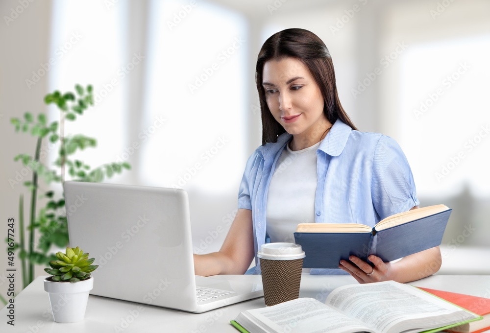 Young businesswoman studying online, watching podcast on laptop, making notes, sitting at work desk. E-learning concept. Young businesswoman studying online, watching podcast on laptop, making notes, sitting at work desk. E-learning concept.