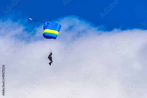 Sky diving parachutist decending against a blue sky photo