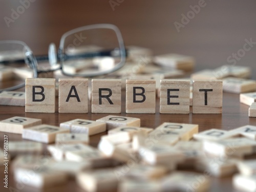 barbet word or concept represented by wooden letter tiles on a wooden table with glasses and a book photo