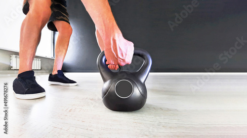 Black cast iron kettlebell on a black background. Black kettle bell with hand