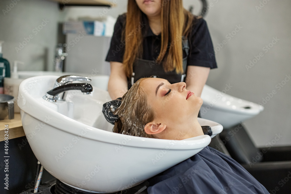 Fototapeta premium Hairdresser washes hair of client in hairdressing salon. Vacation concept, hair care, image change, small business