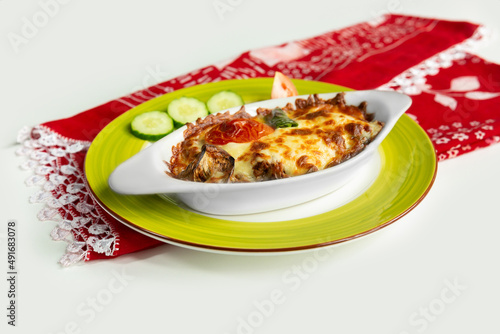Greek dish moussaka with salad in a dish isolated on colorful table cloth top view on grey background