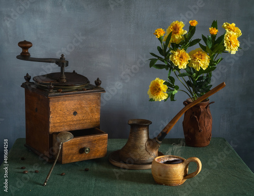 Still life with a bouquet of flowers, a cup of coffee and an old coffee grinder. Vintage.