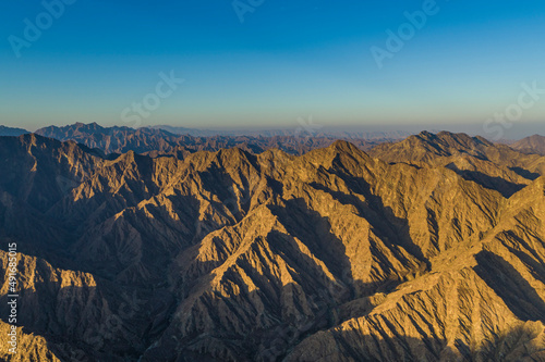 Aerial view of a canyon among the rocky and dry mountains in the desert in Ajman State, United Arab Emirates. photo