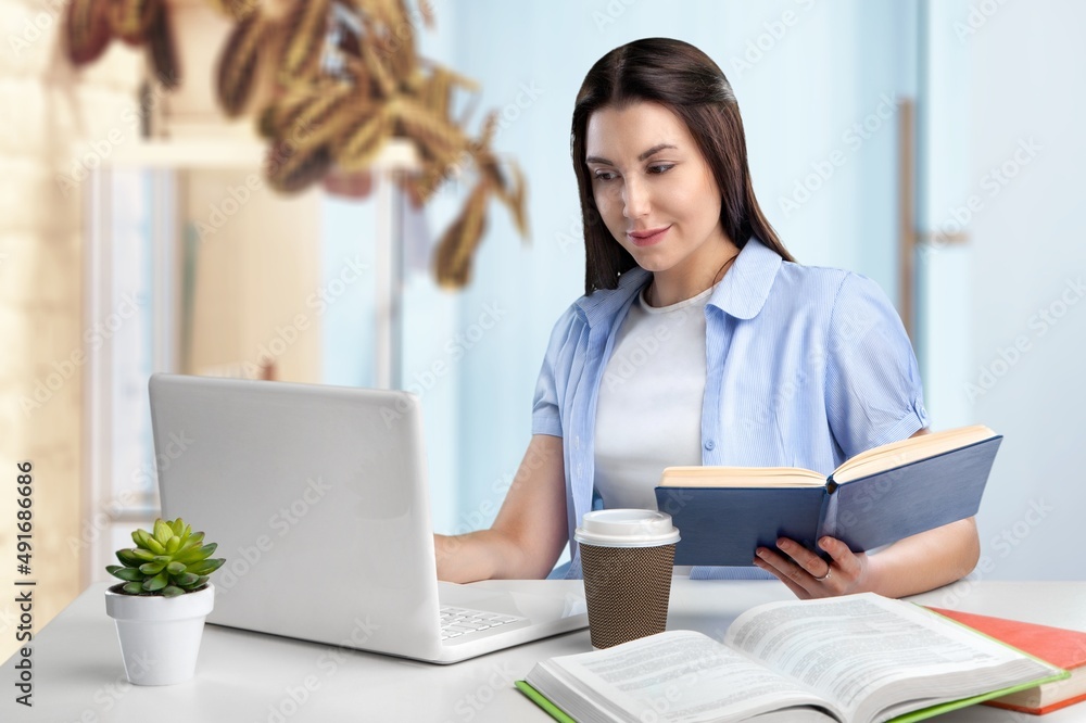 Beauty student girl in studying foreign language, lesson at laptop, reading notes out loud, doing exercises from open book Beauty student girl in studying foreign language, lesson at laptop, reading notes out loud, doing exercises from open book