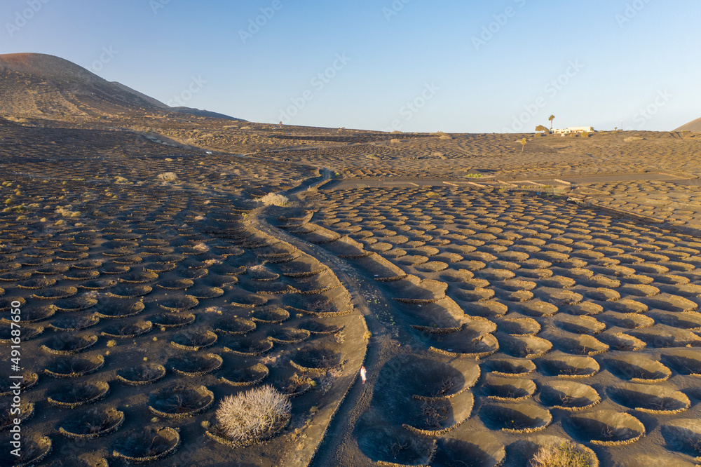 Aerial view of a woman walking among volcano holes formation at Timanfaya national park, Lanzarote Island, Canary Islands, Spain. Aerial view of a woman walking among volcano holes formation at Timanfaya national park, Lanzarote Island, Canary Islands, Spain.