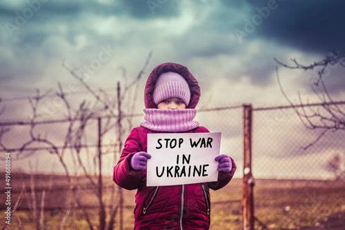Fotografie, Obraz Little refugee girl with a sad look and a poster that says stop war in Ukraine