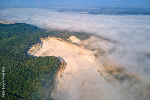 Aerial view of open pit mining site of limestone materials extraction for construction industry with excavators and dump trucks