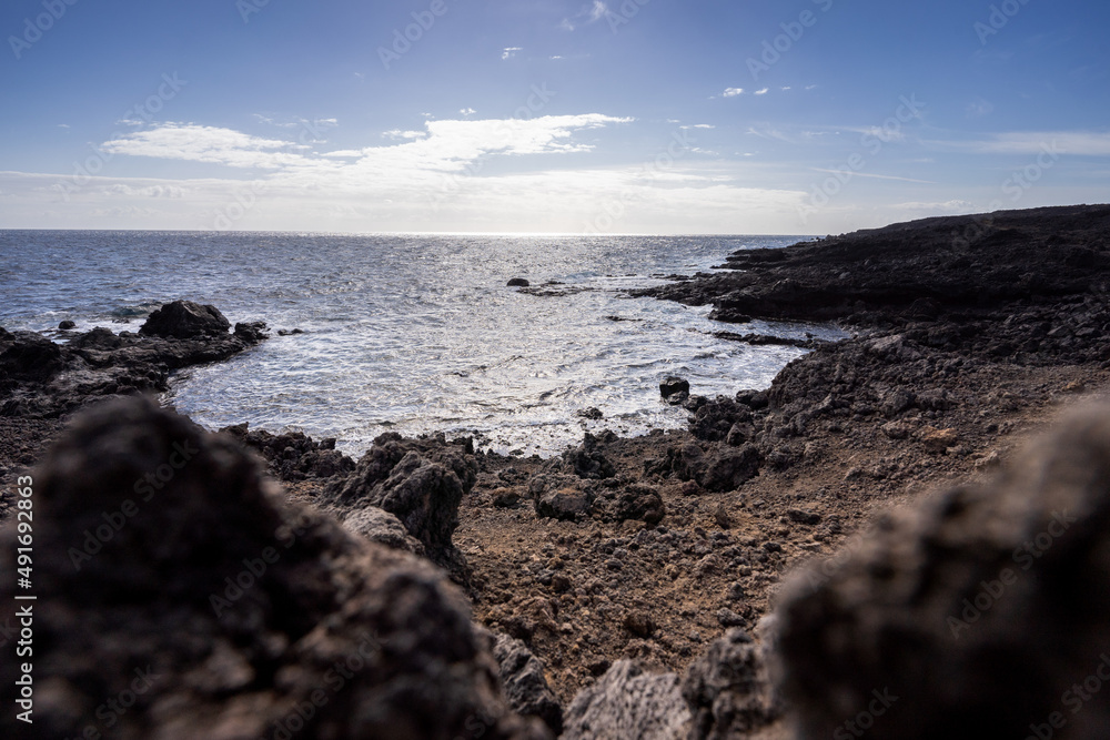 Rocky coast washed by rippling ocean in sunny day Rocky coast washed by rippling ocean in sunny day