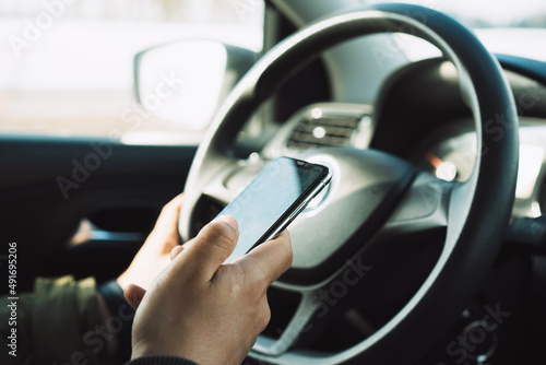 Phone in hand while driving. Phone control while driving. The concept of traffic safety. © Dzmitry