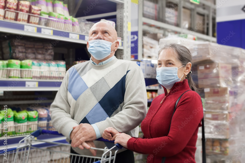 Pensioners in protective masks choosing products in supermarket