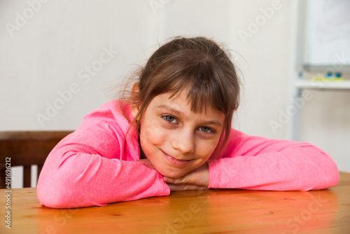 Сute little girl nine years old sitting at table
