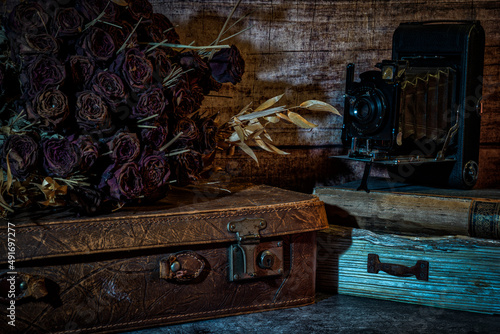 ein alter Leder Koffer mit getrockneten Rosen und einer alten Plattenkamera